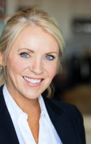 Middle aged businesswoman smiling at the camera. She is calm on a kitchen background